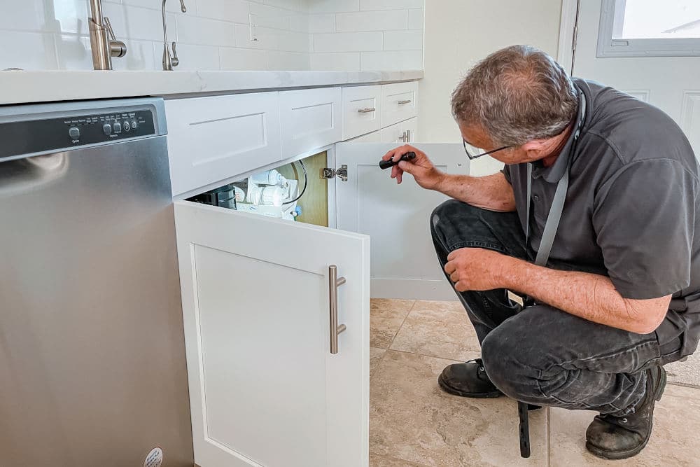 home inspector jeff hunter inspecting for leaks under the kitchen sink